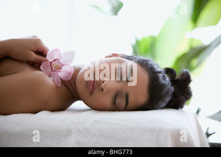 Junge Frau auf Massagetisch mit Orchideenblüten Stockfoto