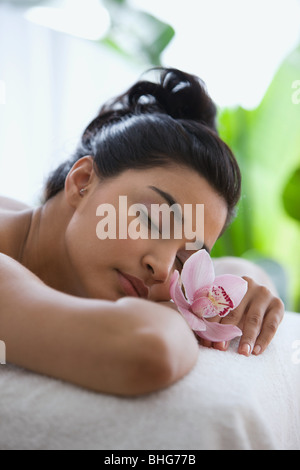 Junge Frau auf Massagetisch mit Orchideenblüten Stockfoto