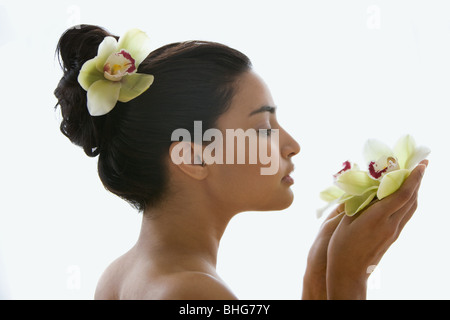 Junge Frau, die eine Orchidee Blume Stockfoto