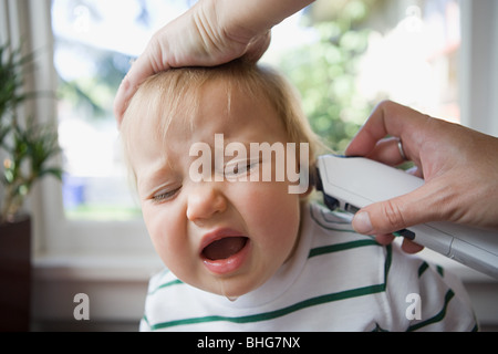 Erwachsenen ins Ohr des schreiendes Baby thermometer Stockfoto