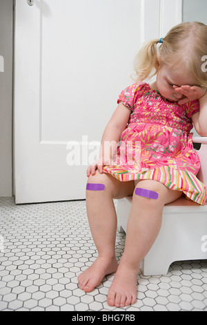 Weinendes Mädchen mit Pflaster am Knie Stockfoto