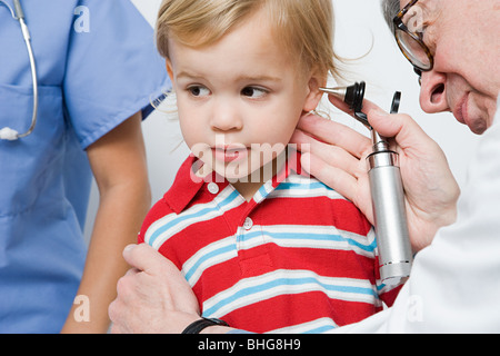 Arzt sucht jungen ins Ohr Stockfoto