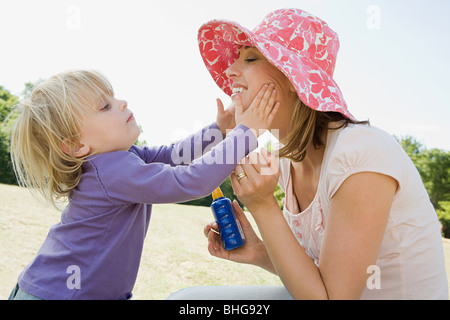 Mädchen, Sonnencreme auf Mutter Stockfoto