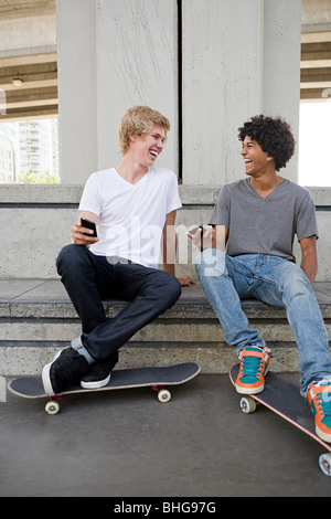 Im Teenageralter mit Handys und skateboards Stockfoto