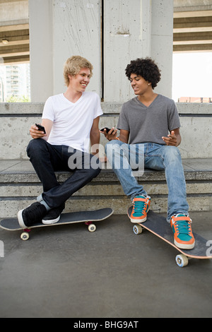 Im Teenageralter mit Handys und skateboards Stockfoto