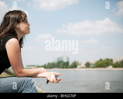 Anhören von Musik durch Fluss Frau Stockfoto