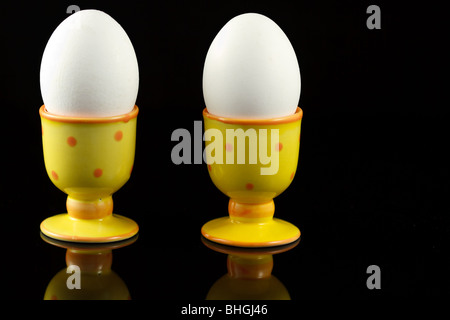 Hühnereier in punktierten Eierbecher auf reflektierenden schwarzen Hintergrund Stockfoto