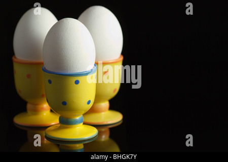 Hühnereier in punktierten Eierbecher auf reflektierenden schwarzen Hintergrund Stockfoto