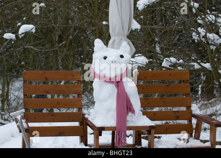Schnee-Schweinchen sitzen auf Sitzbank Stockfoto