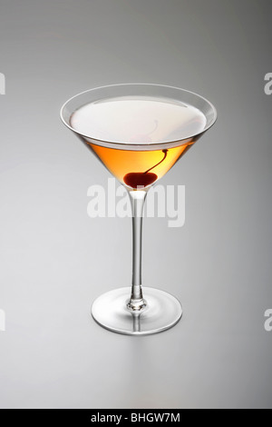 Manhattan cocktail mit Kirsche garnieren auf grauem Hintergrund Stockfoto