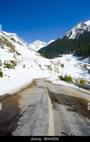 Straße durch die Berge mit Schnee schmilzt Stockfoto