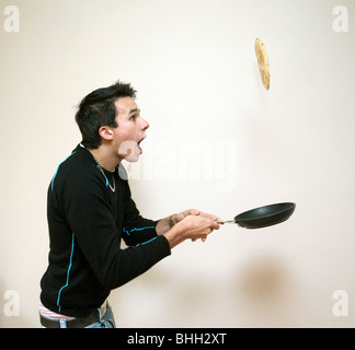 Jugendlicher warf einen Pfannkuchen in einer Pfanne erhitzen, UK Stockfoto