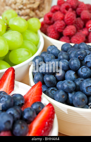 Schalen mit gesunden Frühstück Erdbeeren und Heidelbeeren in Joghurt mit Himbeeren, Heidelbeeren, Weintrauben und Müsli Stockfoto