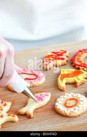 Hausgemachtes Spritzgebäck mit Zuckerguss aus Spritzbeutel verzieren Stockfoto