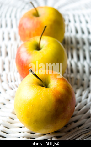 Drei frische Äpfel auf einem weißen alten Korb angeordnet Stockfoto