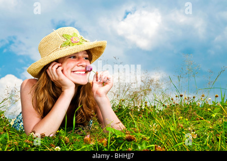 Junge Teenager-Mädchen Verlegung in Sommerwiese ruht Kinn auf Hand riechende Blume Stockfoto