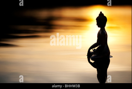 Silhouette der Buddha-Statue, die schwimmend auf ruhige Wasseroberfläche noch bei Sonnenaufgang in Indien Stockfoto