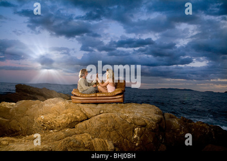 paar Toast Bier auf Couch am Meer Stockfoto