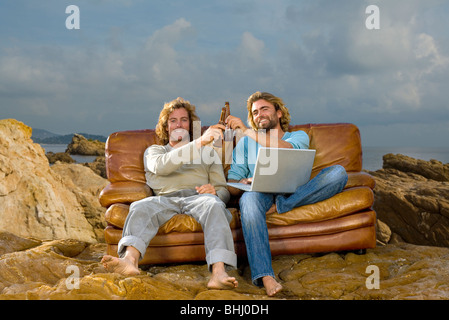 junge Männer mit Laptop und Bier, couch auf Stockfoto