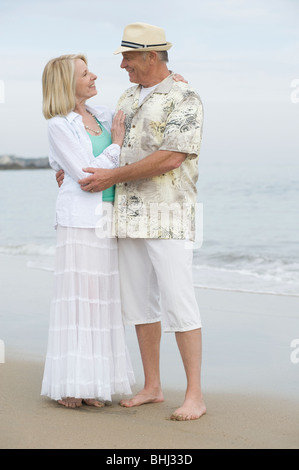 Älteres paar stehen umfassende am Strand Stockfoto