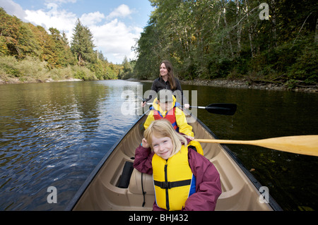 Eine Mutter paddeln in einem Kanu einen Fluss hinunter mit ihren 2 Kindern Stockfoto