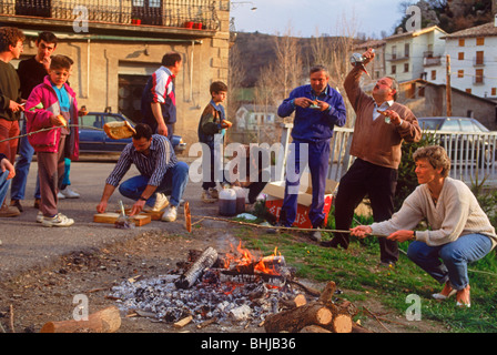 Freunde Rösten Brot über Outdoor-Feuer zu gehen mit Sardinen und Wein in der kleinen Stadt am Karfreitag in spanisches Dorf Stockfoto