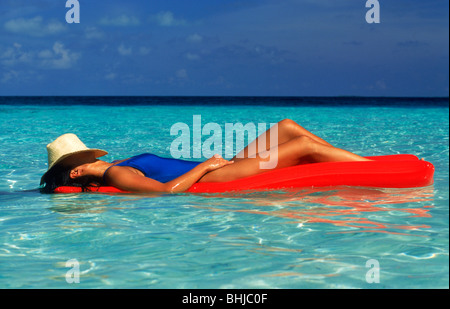 Frau auf Luftmatratze in ruhigen Gewässern wie schweben im Paradies Stockfoto