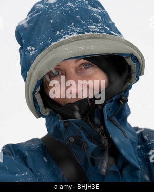 Porträt der Frau im Schnee lächelnd in die Kamera mit Kapuze hautnah. Stockfoto