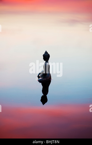 Silhouette der Buddha-Statue, die schwimmend auf ruhige Wasseroberfläche noch kurz vor Sonnenaufgang in Indien Stockfoto