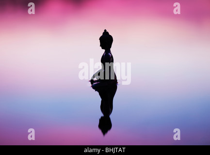 Silhouette der Buddha-Statue, die schwimmend auf ruhige Wasseroberfläche noch vor Sonnenaufgang in Indien Stockfoto