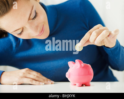 Frau 1 Euro in kleinen Sparschwein setzen. Tiefenschärfe, Textfreiraum Stockfoto