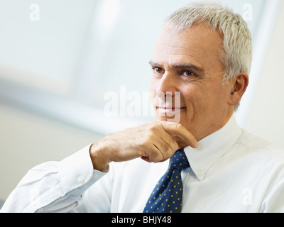 Porträt von reifer Geschäftsmann mit Hand am Kinn, wegschauen. Textfreiraum Stockfoto