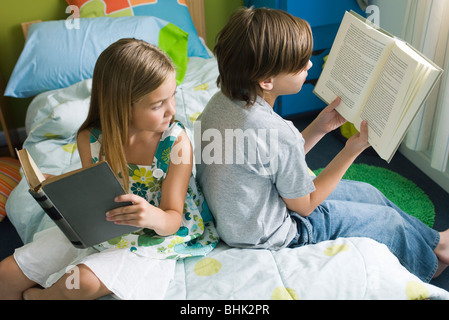 Geschwister zusammen, Mädchen mit einem Blick über die Schulter des Bruders Buch lesen Stockfoto