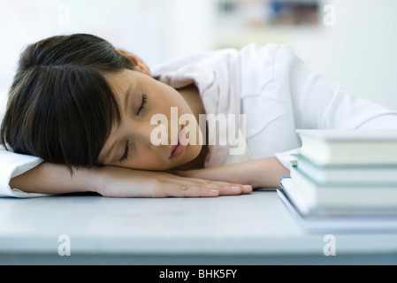 High-School-Schüler mit Kopf auf den Schreibtisch, Stapel von Büchern im Vordergrund ein Nickerchen Stockfoto