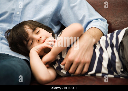 Kleiner Junge mit Kopf in des Vaters Schoß schlafen Stockfoto