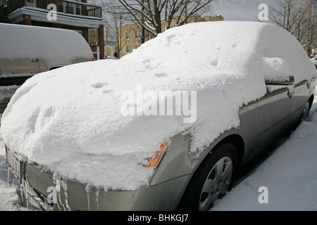 Schnee bedeckt und umgibt ein Auto auf einer Straße im winter Stockfoto