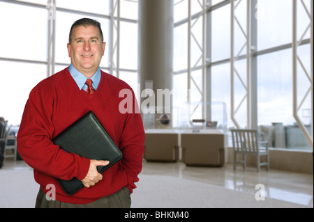 Ein Geschäftsmann steht mit seiner Ledermappe in eine große Lobby warten auf ein Treffen Stockfoto
