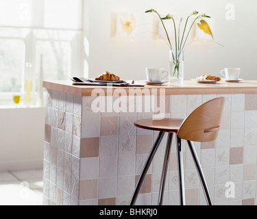 Chrom + Holz Hocker an der Theke auf Stein gefliest Halbinsel Einheit in Wirtschaft-Küche Stockfoto