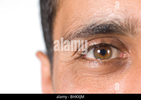 Nahaufnahme von einem ethnischen Mannes Auge Blick in die Kamera vor einem weißen Hintergrund Stockfoto