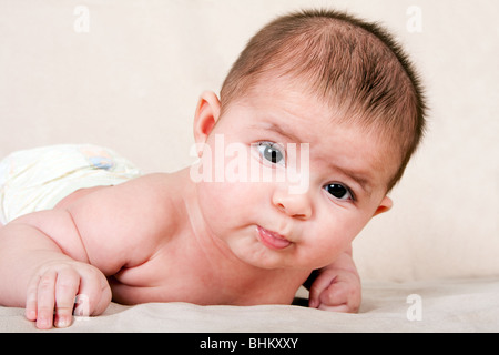 Süße kaukasische Hispanic Baby Kleinkind Handauflegen Bauch Hubkopf machen lustige Ausdruck. Stockfoto