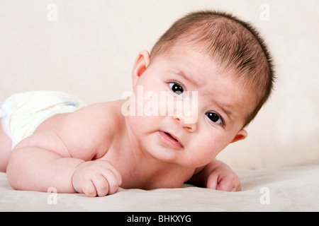 Süße kaukasische Hispanic Baby Kleinkind Handauflegen Bauch Hubkopf machen lustige Ausdruck. Stockfoto