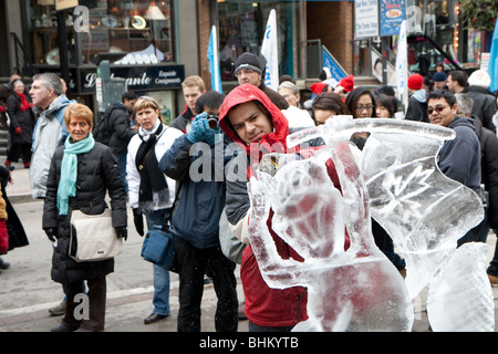 Ein Ice Carving-Künstler arbeitet an seine Eisskulptur, während das Publikum auf der Straße sehen Sie auf Stockfoto