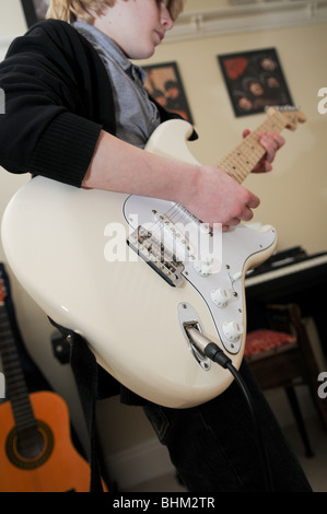 Gitarristen spielen eine Creme Fender Stratocaster mit Klavier im Hintergrund und Beatles Alben an der Wand. Stockfoto