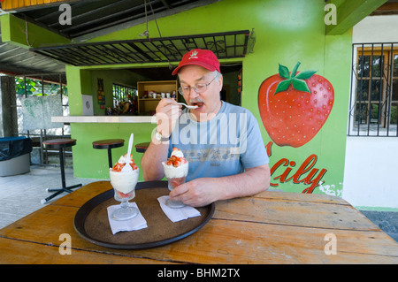 Mann, der Erdbeeren und Rahm in einer Tasse Panamaf isst Stockfoto