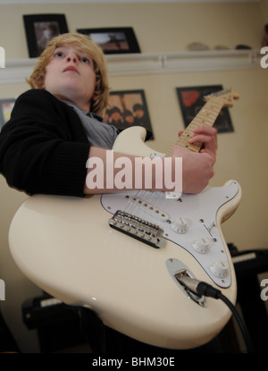 Gitarristen spielen eine Creme Fender Stratocaster mit Klavier im Hintergrund und Beatles Alben an der Wand. Stockfoto