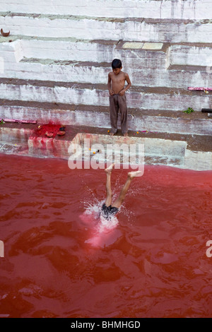 Jungen im Manikarnika Brunnen Baden getönt rot während Holi-fest. Varanasi. Indien Stockfoto