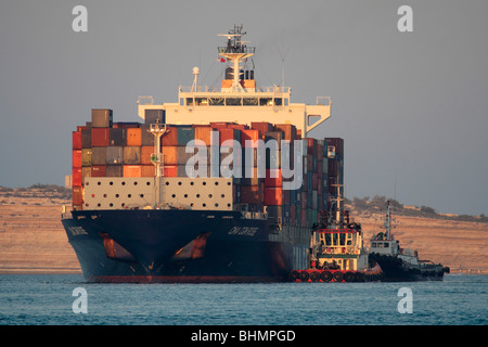 Internationalen Handel durch den Seeverkehr. Containerschiff von Schleppern begleitet, wie es in den Malta Freeport. Liefer- und Globalisierung. Stockfoto