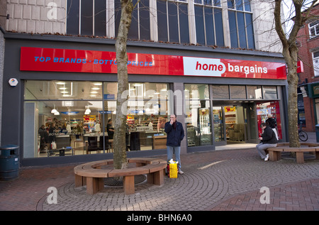 Externen Shop Fassade Home Schnäppchen Shop wo Top-Marken - Preisuntergrenzen auf schattigen Baum Menschen beim Einkaufen Hautpstraße gesäumt Stockfoto