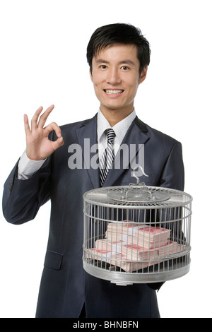 Geschäftsmann hält Vogelkäfig mit Geld gefüllt Stockfoto
