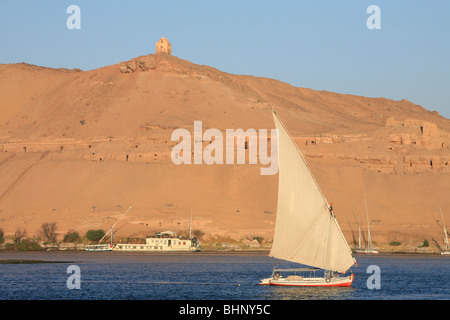 Feluke Segeln in den frühen Morgenstunden auf dem Nil vorbei die Gräber der Adligen in Assuan, Ägypten Stockfoto